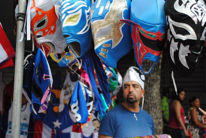 Man in front of lucha masks at a festival in NYC